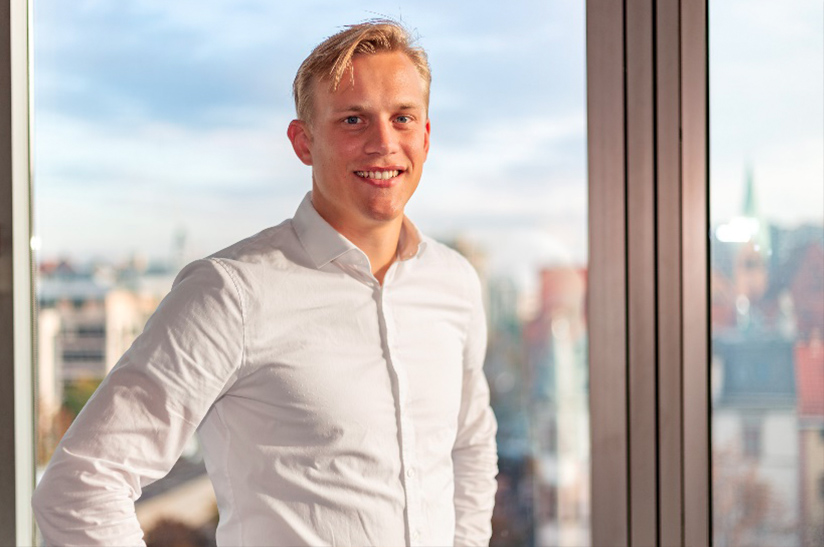 Goehner_Beitragsbild_online Kopie Nico Göhner, Referent der Geschäftsführung bei AIT Goehner, lächelt vor Fenster.