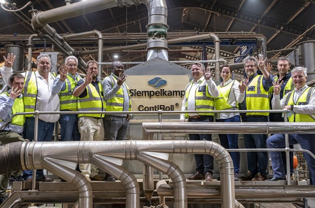 Siempelkamp-Mitarbeiter stehen auf einer Maschine und freuen sich