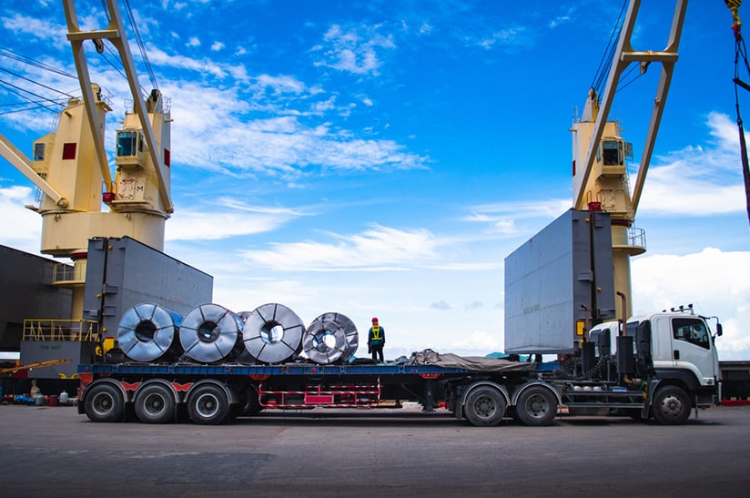LKW transportiert Metallrollen im Hafen, Thema Fahrermangel, DIHK (Symbolbild)