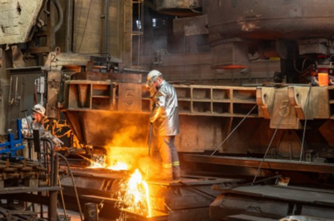 ArcelorMittal-stahlwerk-szene-transformationsgipfel-aufruf: Arbeiter in Schutzkleidung bei flüssigem Metall.