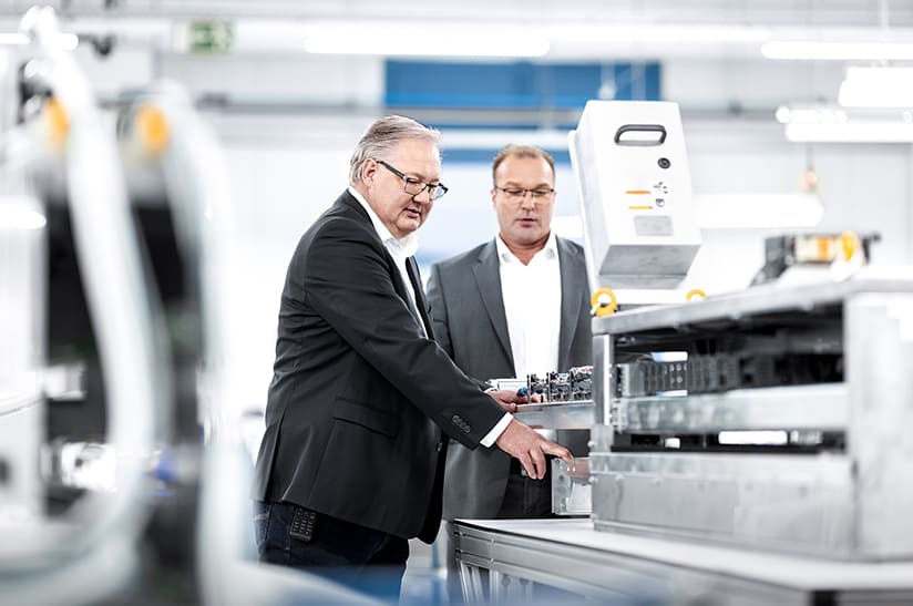 Hary Kosciesza, Business Development Manager bei technotrans (links) und Reinhard Skricek, Sales Manager bei technotrans, an einer spray.xact-Sprühbeölungsanlage.