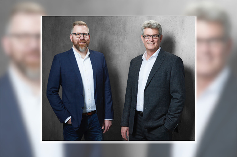 Nordwest (web) das Bild zeigt zwei weiße, bebrillte Männer im Anzug. Links im blauen Anzug steht Marc Gronau, zweiter Geschäftsbereichsleiter Bau & Europa. Er wird die Nachfolge von Geschäftsbereichsleiter Stefan Thiel (rechts, grauer Anzug) bei Nordwest antreten.
