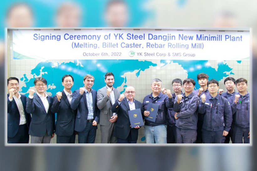 Das Bild zeigt jubelnde Männer (Europäer und Asiaten, viele im Sakko) die sich über den Abschluss eines Geschäfts zwischen YK Steel und SMS group freuen.