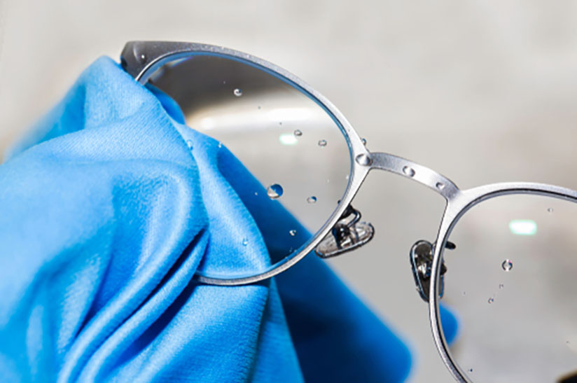 Cleaning,Glasses,Lens,To,Be,Clean,,Clear Das Bild zeigt eine Brille aus Edelstahl, die mit eibem blauen Tuch gereinigt wird. Alleima will die Reste aus der Herstellung solcher Brillen recyceln.