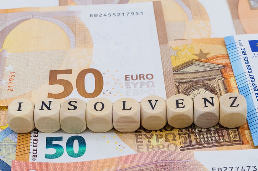 shutterstock_1538401625 web Das Bild zeigt neun Würfel, die nebeneinander liegen und das Wort Insolvenz bilden. Unter den Würfeln liegen Geldscheine. In dem dazugehörigen Artikel geht es um die Insolvenzantragspflicht.