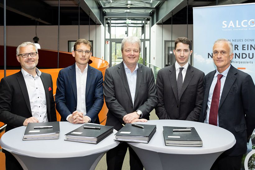 Das Bild zeigt fünf weiße Männer in Business-Outfits, die hinter Stehtischen stehen. Einer von ihnen gehört zur Salzgitter AG.