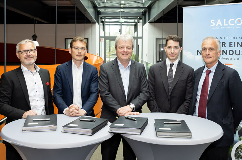 230524-pm-vergabe-drp-web Das Bild zeigt fünf weiße Männer in Business-Outfits, die hinter Stehtischen stehen. Einer von ihnen gehört zur Salzgitter AG.