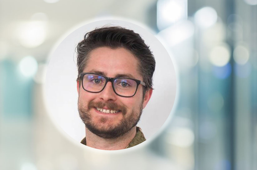 Das Bild zeigt in einem runden Ausschnitt das Kopfporträt des MPI-Forschers James P. Best. Der Hintergrund ist eine unscharfe Aufnahme.