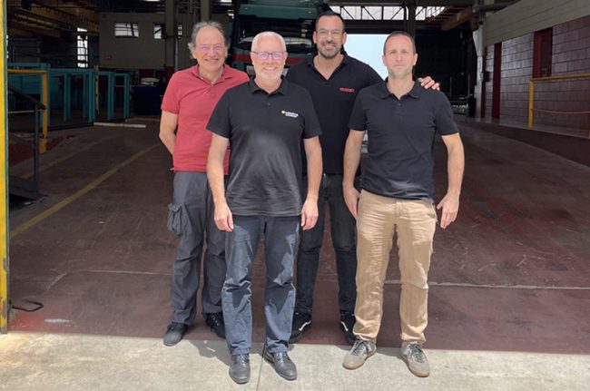 Das Bild zeigt vier Männer mittleren Alters in Polohemden, vor einer leeren Lagerhalle stehen. s handelt sich dabei um die Führungskräfte von Manxa Ferros und Kaltenbach Solutions.