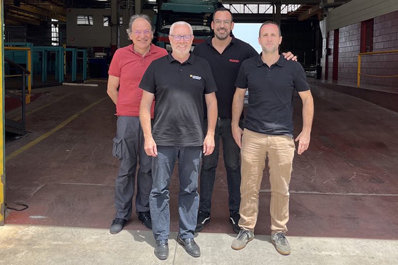 Das Bild zeigt vier Männer mittleren Alters in Polohemden, vor einer leeren Lagerhalle stehen. s handelt sich dabei um die Führungskräfte von Manxa Ferros und Kaltenbach Solutions.