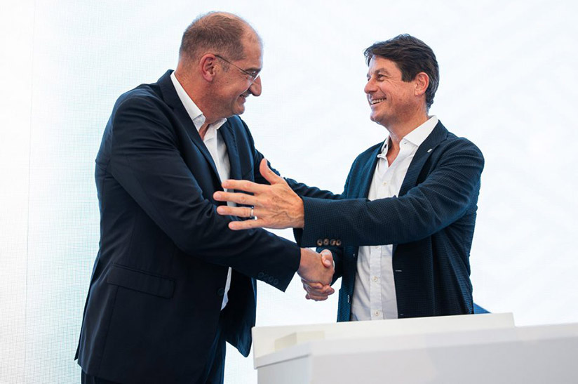 Zwei Männer in Anzügen, die beiden Leiter von Seven Refractories und RHI Magnesita, schütteln sich lächelnd die Hände