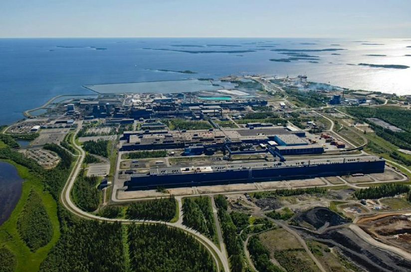Outokumpu-Tornio (web) Das Bild zeigt das Werk von Outokumpu im finnischen Tornio aus der Adlerperspektive. Im Vordergrund ist etwas grüne Landschaft zu sehen, dann kommen die Anlagen und im Bildteil die See.
