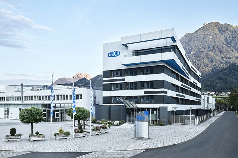 Das Bild zeigt ein Bürogebäude vor einem Bergpanorama. Es handelt sich dabei um den Sitz von Tyrolit.