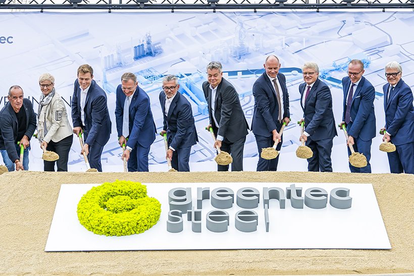 Das Bild zeigt eine Reihe männlicher Führungskräfte, darunter eine Frau, die den symbolischen ersten Spatenstich für einen Neubau bei Voestalpine in Linz setzen.
