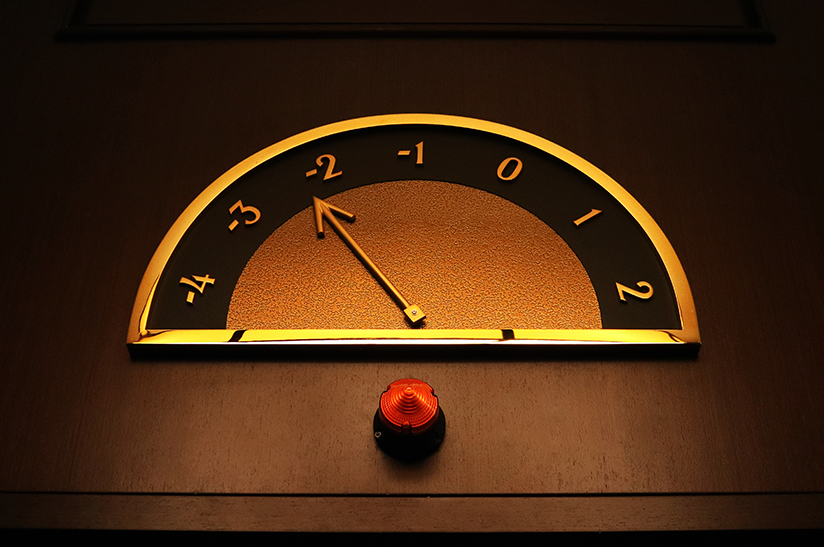 Die stahlproduktion-arcelormittal-blechexpo-2021 2023 in Deutschland sank deutlich. Dem Trend entsprechend zeigt das Bild die Anzeige der Etagennummer eines Aufzugs auf hölzerner Textur. Der Zeiger ist golden und die Zahlen sind altmodisch.