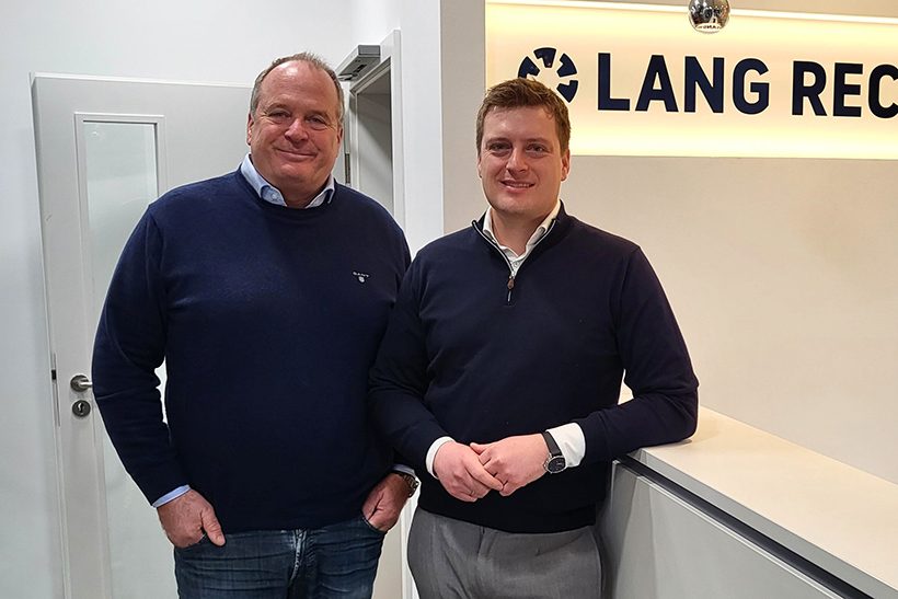 Das Bild zeigt zwei weiße Männer am Empfangstresen eines Büros – es handelt sich um Martin Lang und Maximilian Lang von Lang Recycling.