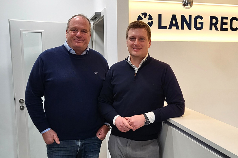 Das Bild zeigt zwei weiße Männer am Empfangstresen eines Büros – es handelt sich um Martin Lang und Maximilian Lang von Lang Recycling.