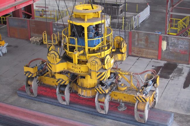 Das Bild zeigt einen Zangenkran, der eine glühende Bramme ablegt. Dabei kommt Technik von Symeo zum Einsatz.