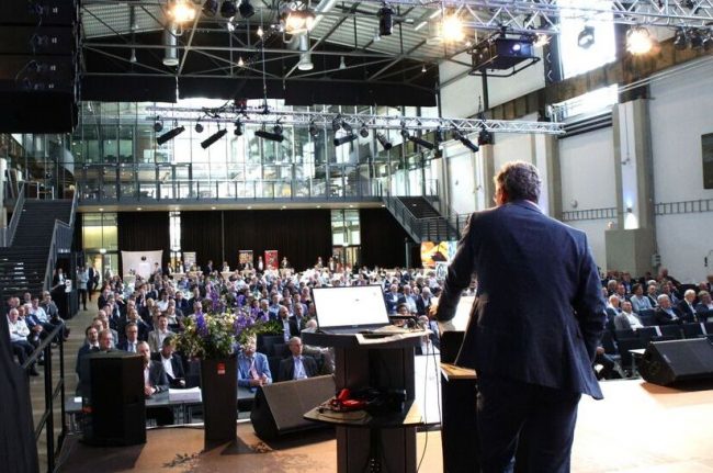 VDEh-StahlTag_(web) Impression vom VDEh-StahlTag 2025: zu sehen ist der Rücken eines Redners auf der Bühne, der Blick geht in die Halle und zeigt viele Zuhörer