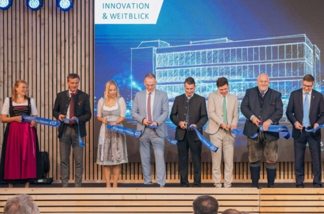 Das neue Temperaturmesstechnik-Zentrum von Endress+Hauser in Nesselwang (Zeichnung im Hintergrund) bietet eine Nutzfläche von 3.500 Quadratmetern und wurde traditionell mit einem Scherenschnitt eröffnet.