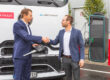 Felix Schmitz, CEO von Kloeckner Metals Germany (li.) erhält von Johannes Franz (Leiter Nutzfahrzeugzentrum Daimler Truck AG, re.) einen überdimensionalen Schlüssel. Die beiden stehen vor einem eActros 600.
